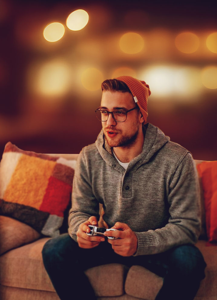 Man playing video games on couch, bokeh background