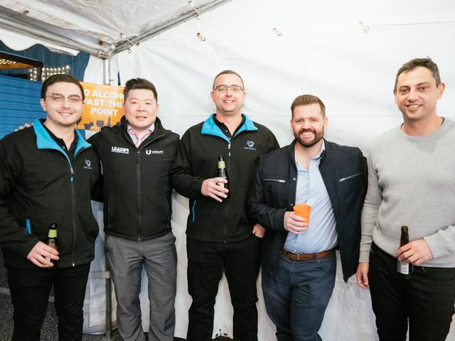 Five men holding beers in a tent at Pentafest