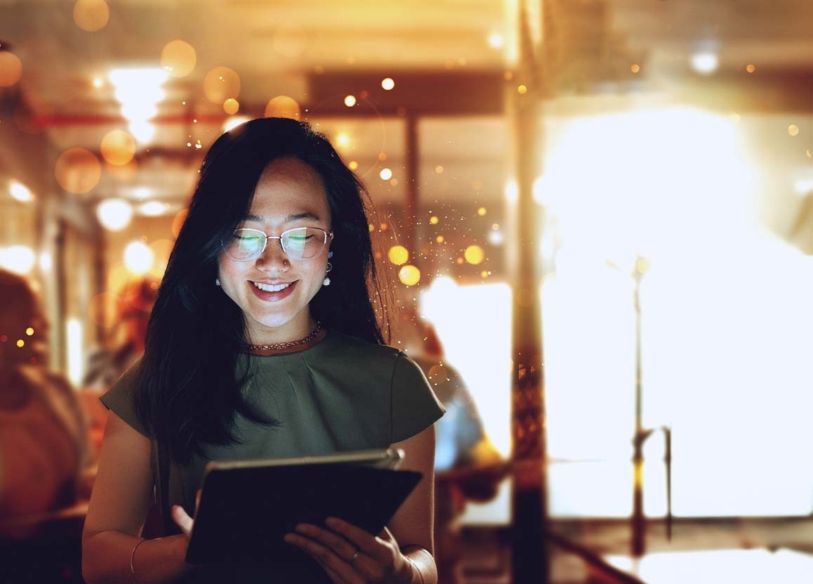 Smiling woman using iPad in busy coffee shop, bokeh background