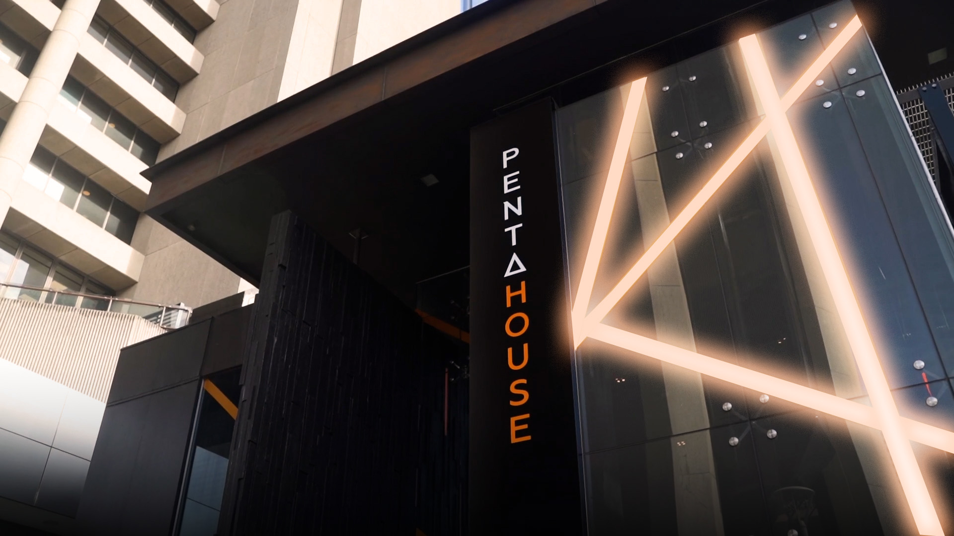 Building with glowing neon lines and Pentahouse logo running vertically down it